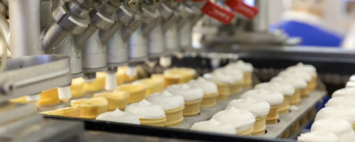 Ice cream cones being filled in factory.