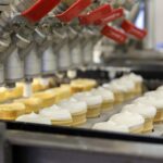 Ice cream cones being filled in factory.