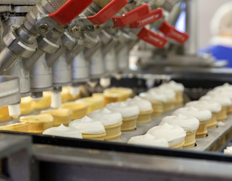 Ice cream cones being filled in factory.